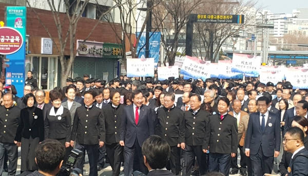 주요 인사들이 학생들 뒤에 서서 함께 행진하고 있다.