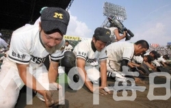경기에 진 선수들이 고시엔 구장의 흙을 퍼담고 있다. 일본교도통신