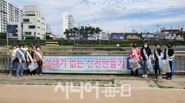 참여 회원이 「쓰레기 없는 대구 신천 만들기」 플래카드 곁에서 쓰레기를 담은 비닐봉투를 들고 사진을 찍고 있다.