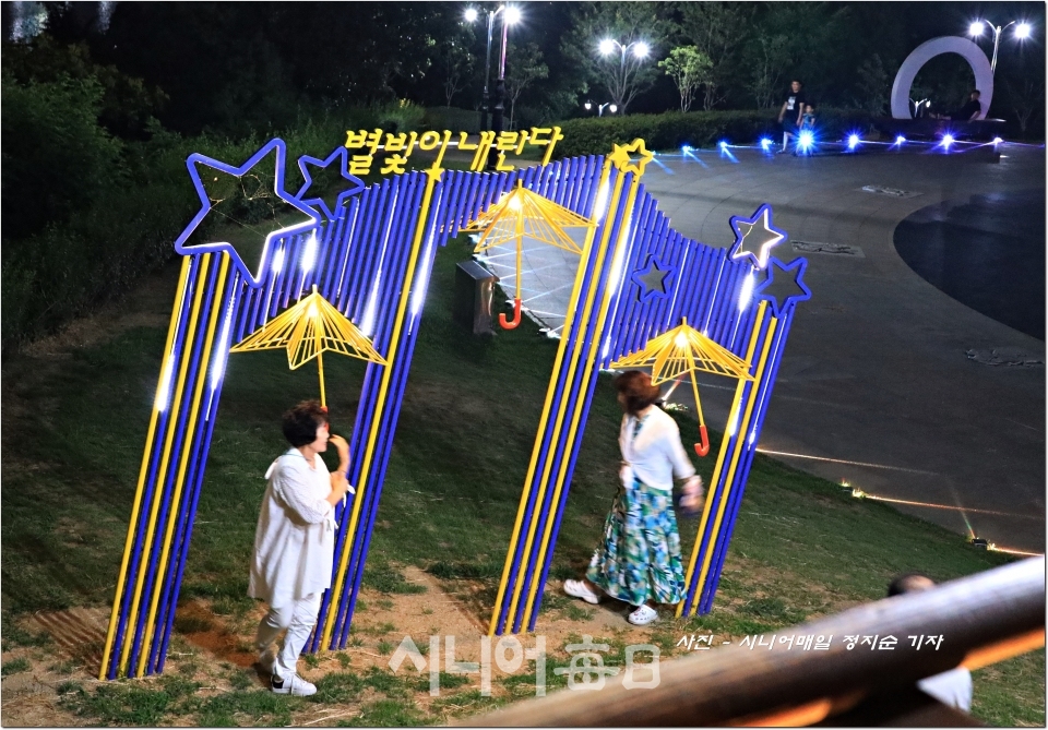 해맞이동산 정상 원형광장에 설치되어 있는 별빛내인다 조형물에서 산책나온 시민들이 조형물 우산아래로 돌아보고 있다.  정지순 기자