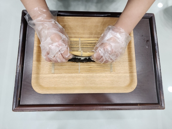 8. 김밥을 반으로 접어 꽃잎 모양이 될 수 있도록 김 끝쪽 부분을 꾹 눌러 모양을 만들어준다.