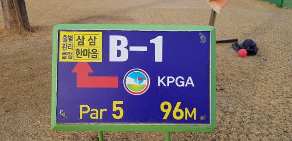 표지판에 B코스 1번 홀이고, 파5이며, 홀컵까지 거리가 96m임을 표시하고 있다.
